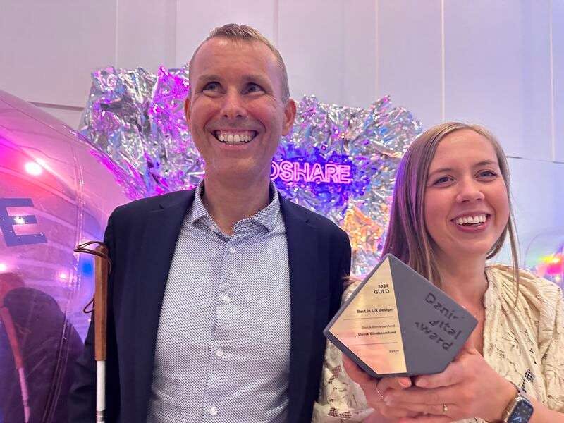 Stein Erik og Anna smiler stort med guldprisen for "Bedst i UX Design" i hånden, ved Danish Digital Award.