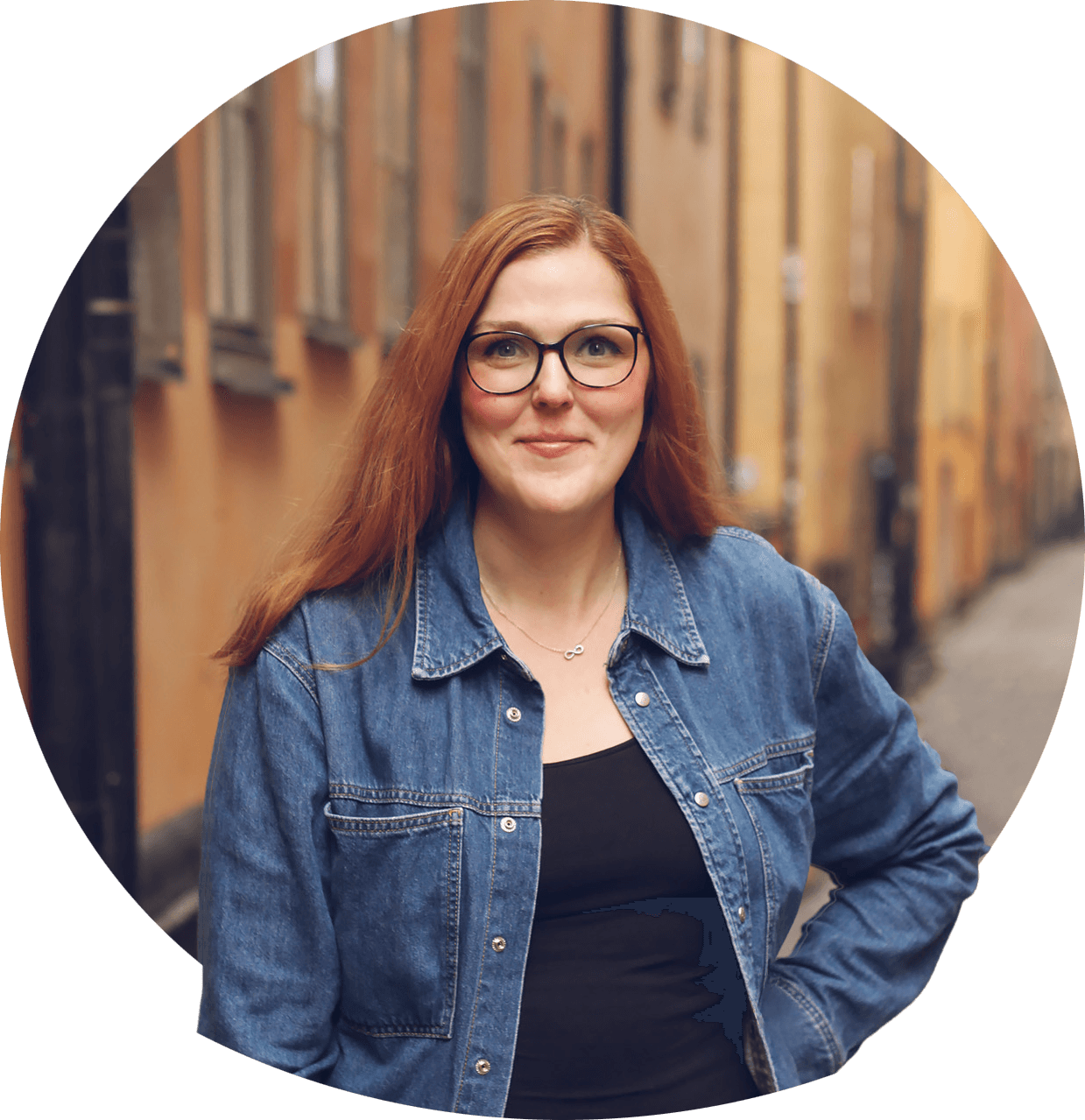 Line med briller og mellemblondt hår i hestehale, smilende, iført mørk bluse. Foto.