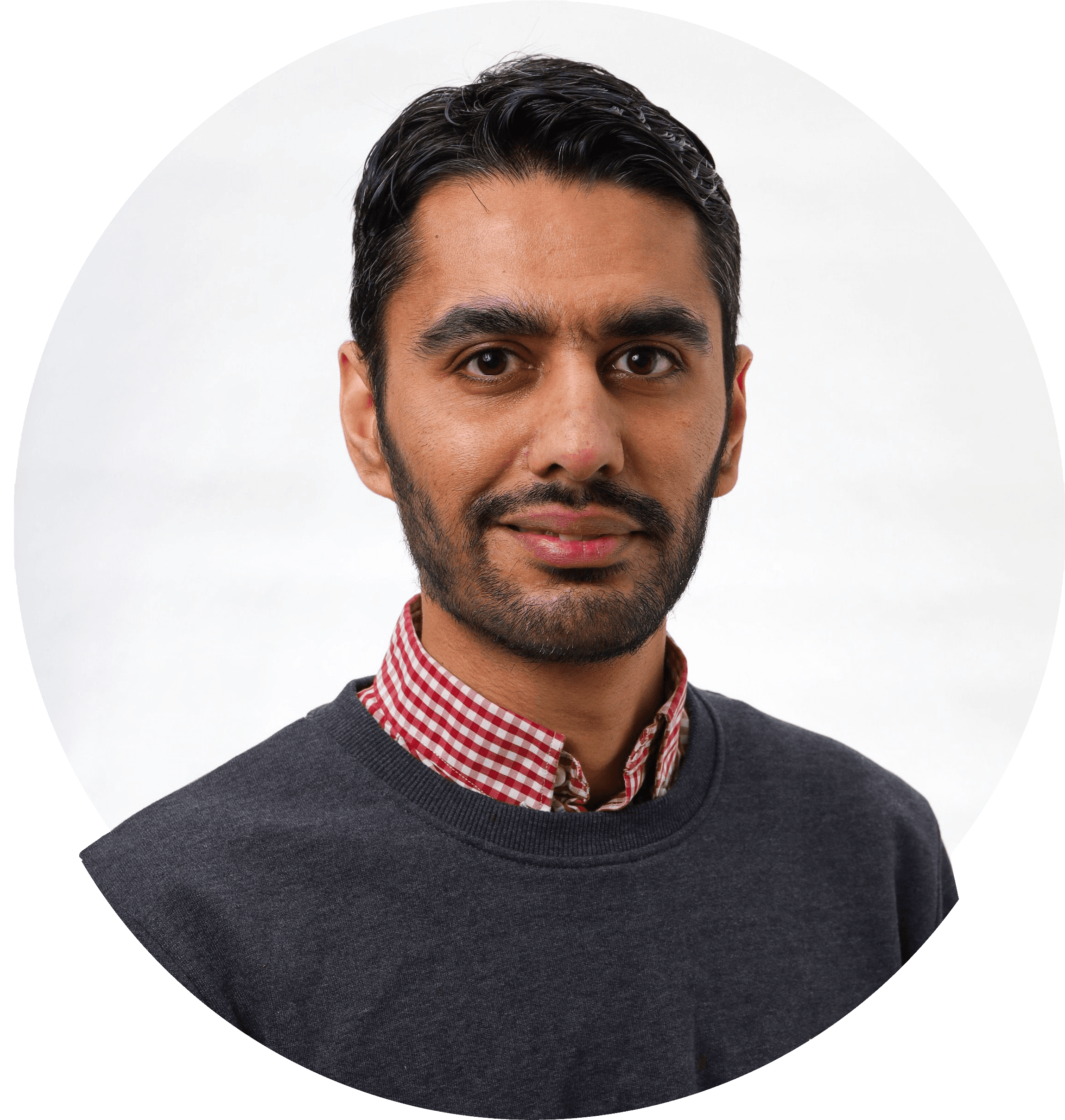 Danial smilende med mørkt hår og skæg i lyserød skjorte og mørk trøje. Foto.